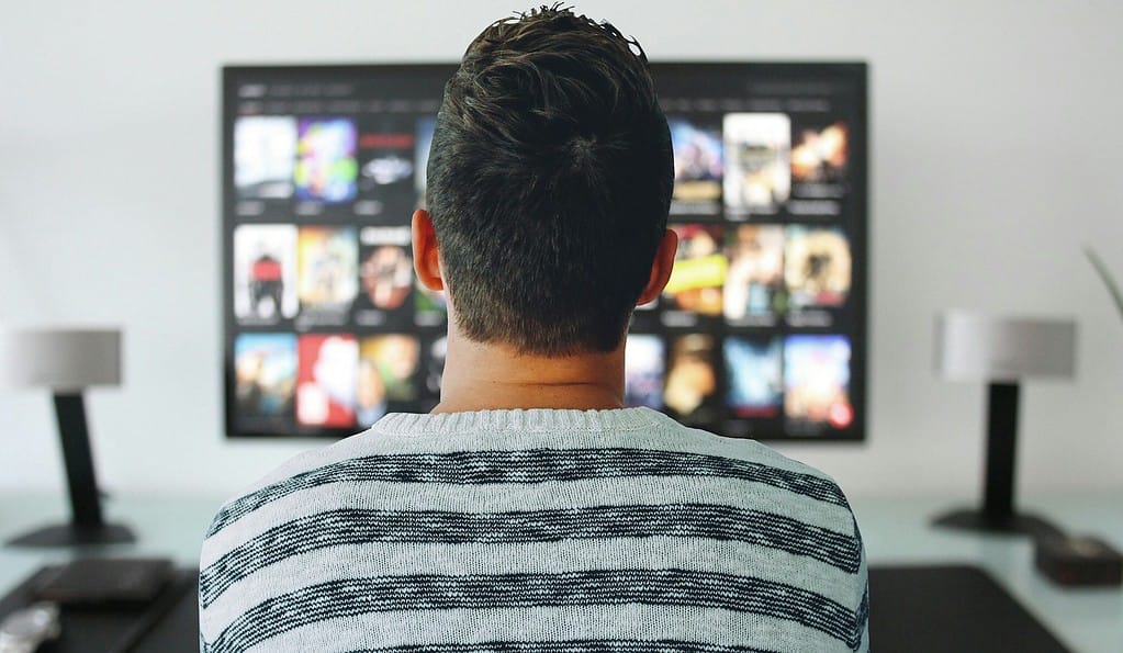 Un homme regardant une série télévisée sur un écran de télévision pour apprendre l'anglais.