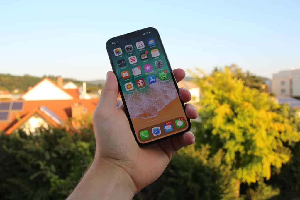A man holding up a iPhone displaying some of the best apps for French learning.