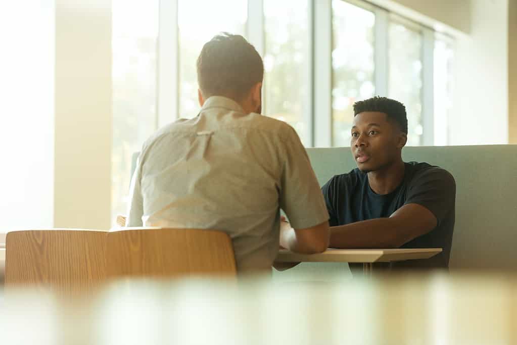 Two young men enjoying a lively French conversation, discussing the best French conversation starters to break the ice and start making friends.