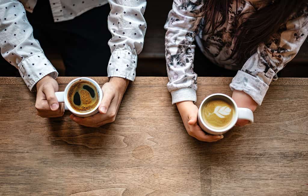 Deux amis profitant d'un café tout en pratiquant la conversation anglais traduction, une étape clé vers la maîtrise de la langue.